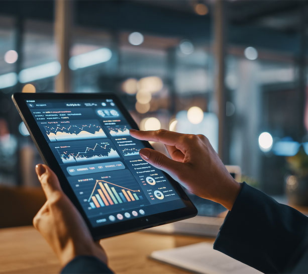 Hands interacting with a tablet displaying financial charts and data dashboards, representing data analysis, business intelligence, and digital decision-making.