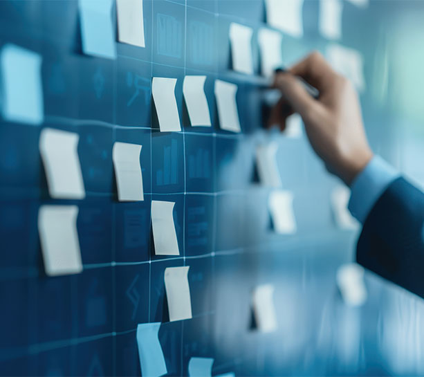 Hand placing sticky notes on a glass board, representing brainstorming, planning, and organizing ideas in a modern workspace